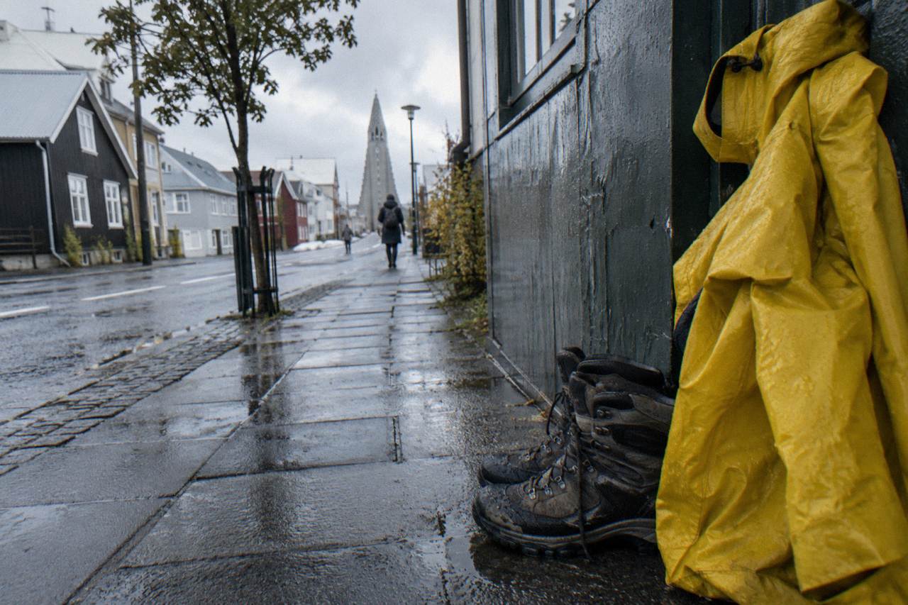 Rain jacket and walking boots on a bench beside a wet Reykjavik street