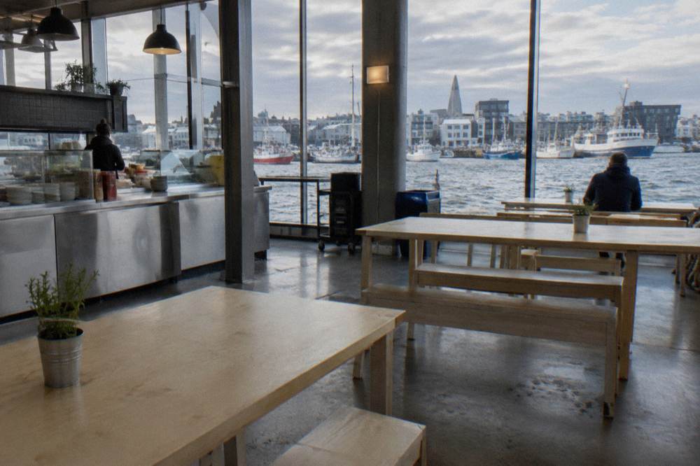 Food hall interior with counter service and empty communal tables in daylight